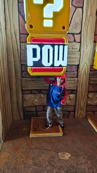 Sammy standing under a POW sign