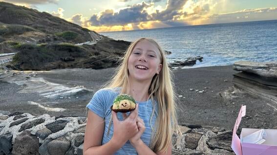 Wish kid Nora smiling brightly standing on a black sand beach
