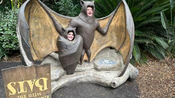 Ava smiling in a bat statue