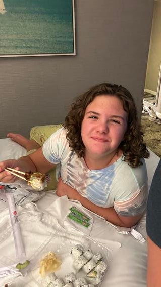 Ava eating sushi in her hotel room