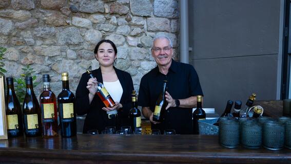 two individuals each holding a bottle of wine at the Abbott's Passage Winery