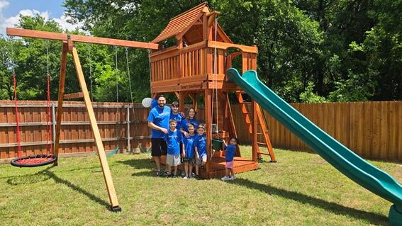 Family standing in front of backyard playset