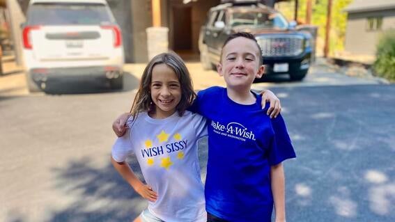 two children smiling in a hotel parking lot