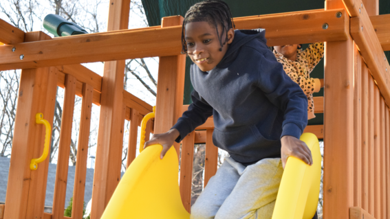 Davaughn sliding down a yellow slide