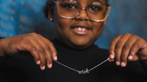 Wish child holding "Wish" bracelet