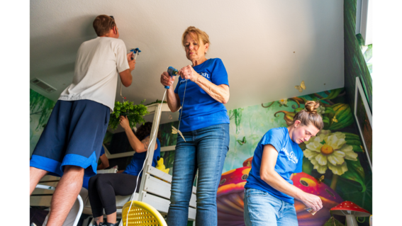 Jan hanging butterflies for wish kid Kyra's enchanted forest bedroom.