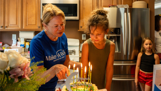 Jan showing wish kid Kyra the reptile-themed cake she brought her.