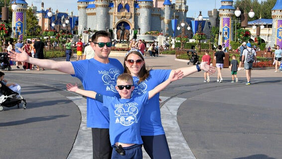 Noah and his family pose in front of the castle at Disney World