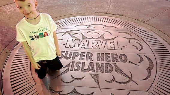 Noah poses with the Super Hero Island seal at Disney World