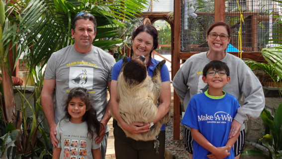Joshua and his family pose with Sarah Stuck, On-Site Keeper at Nurtured by Nature, and a sloth