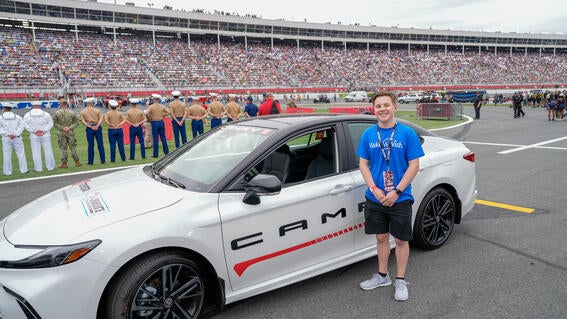 Caleb standing in front of a racecar