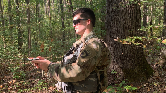 Wish alum Conrad walking through the forest in his US Army fatigue.