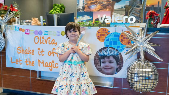 Little girls stands in front of a sign
