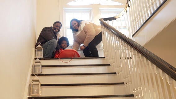 Austin and his parents at the top of the staircase with Austin about to sled down.