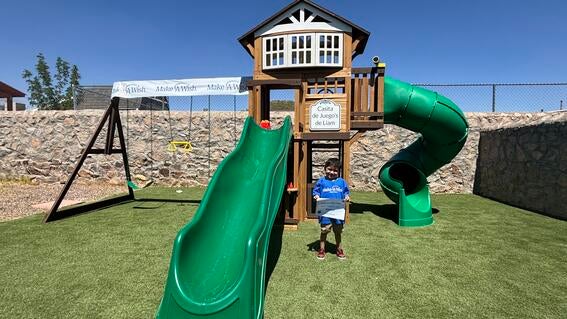 wish kid standing in front of backyard playset