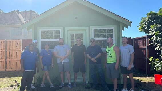 volunteers standing in front of she shed