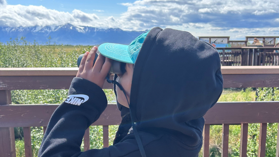 Aanya looks through binoculars on her wish trip to Alaska