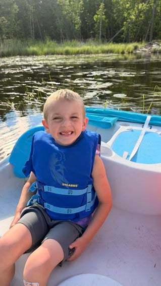 Wish kid Silas in a lifejacket on a boat