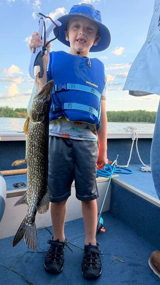 Wish kid Silas holding a fish on a boat