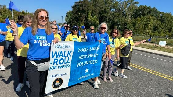 Image shows a group of volunteers walking holding a banner