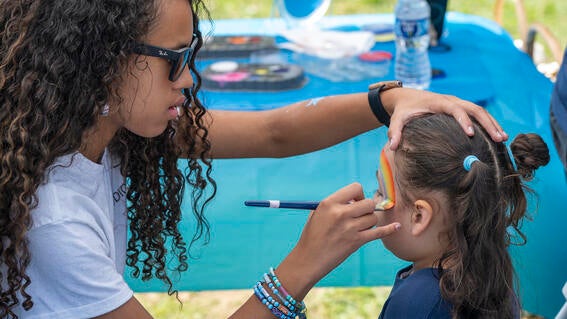 Woman paints a child's face at Walk for Wishes