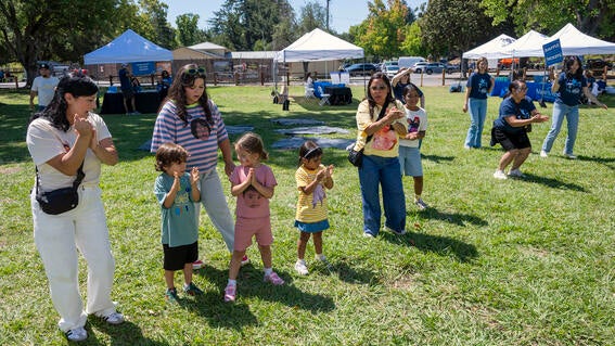 Adult and child walkers dance in a line on the lawn