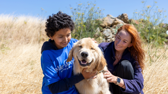 Anika and Karin smiling as they pet, Rudder. 