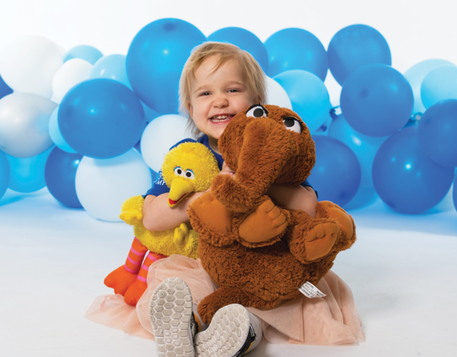 Elise smiles with her Sesame Street friends