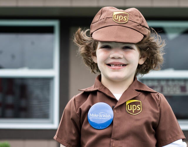 Wish kid JoJo, wearing a brown UPS uniform, smiles for the camera