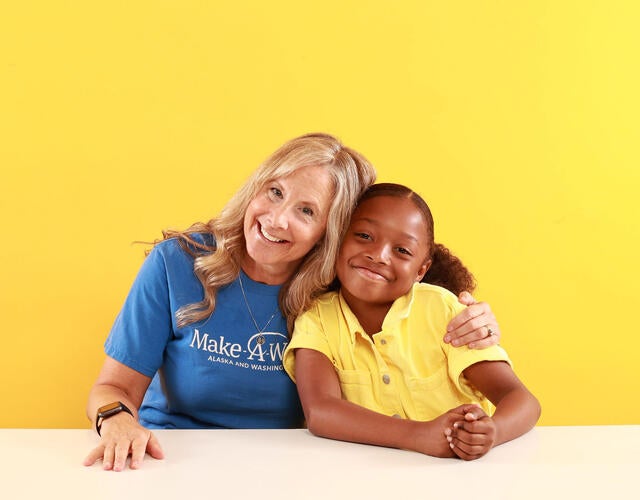 Wish volunteer and wish kid hugging and looking at camera