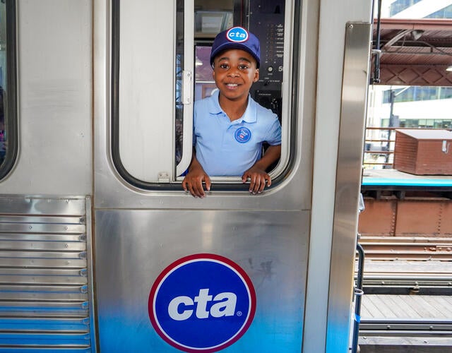 Wish kid Idris standing in window of CTA train looking at the camera