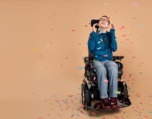 boy using wheelchair with confetti falling around him