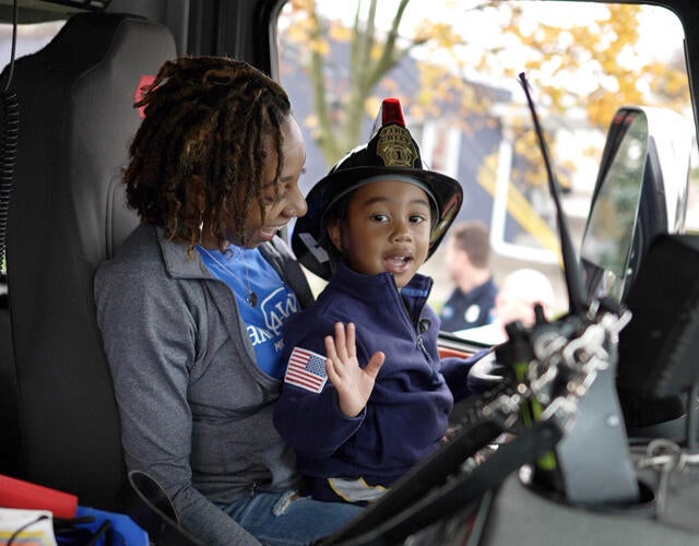 wish kid Jayce sitting in the driver's seat of a firetruck on his mom's lap