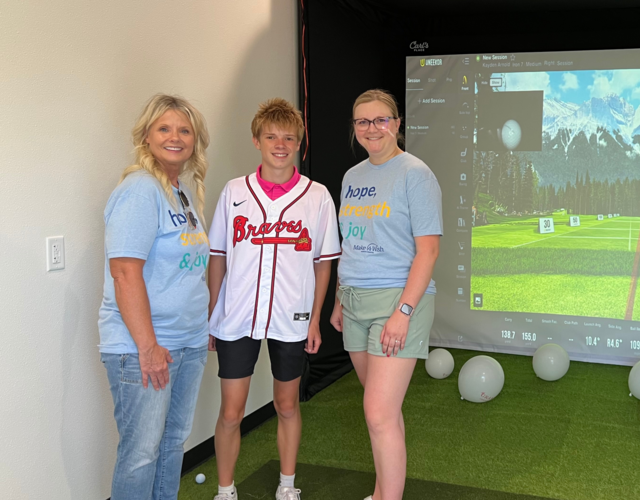 Wish kid Kayden with his wish granters in front of his golf simulator