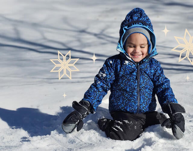 boy in blues snow suit playing in the snow