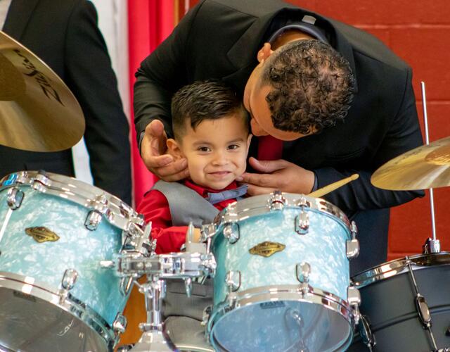 Wish kid Jacob with dad sitting at his new drum set