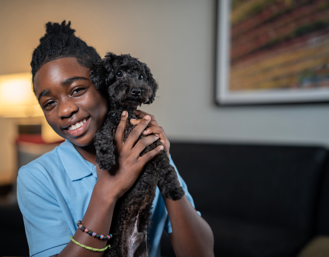 Wish kid Bryce holding his new black toy poodle puppy