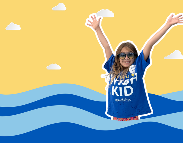 A young child with sunglasses and a blue "I'm a Wish Kid" t-shirt smiles with arms raised in front of a yellow sky with cartoon clouds and blue wavy water.
