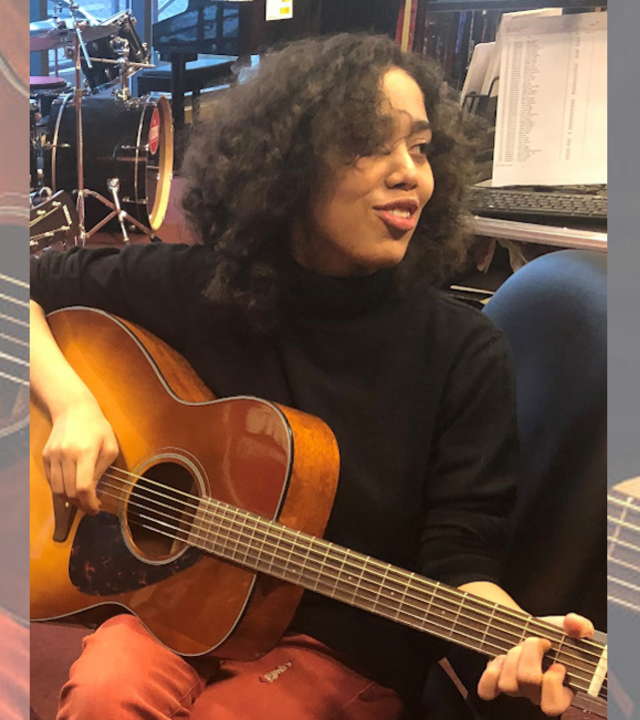 Alayja plays her guitar during a lesson