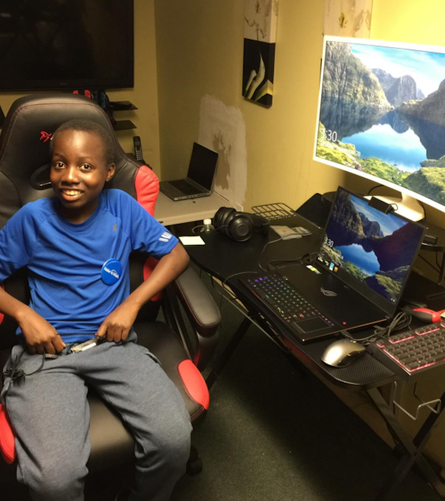 Matthew sits proudly in his new gaming chair in front of his new computer in his bedroom.