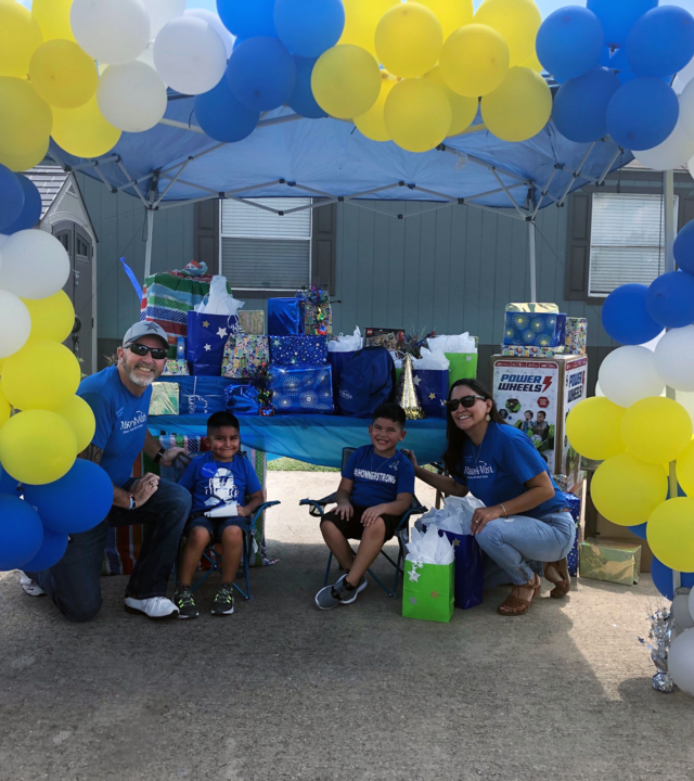 Wish Kid Khonner and brother Koda with Make-A-Wish Volunteers under a balloon arch.