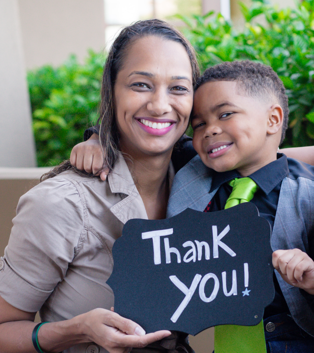 Wish Mom and kid hold a 'thank you' sign