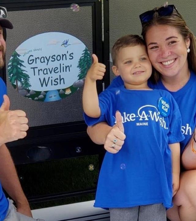 Grayson and his parents smile in front of his pop-up camper
