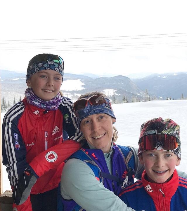 Dr Carlson sits between her two children in a cabin, with snow and trees in the background