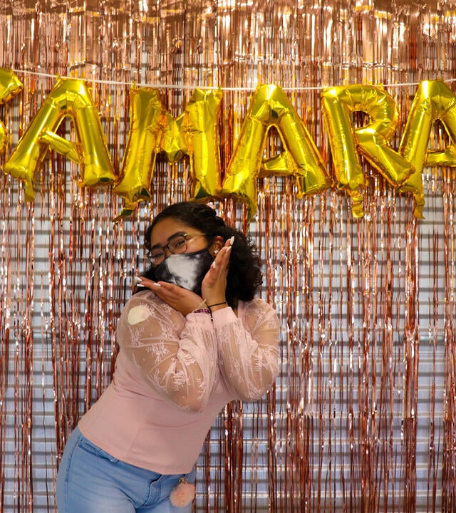 Wish kid Samara posing and smiling in front of gold balloons that spell out "Samara"