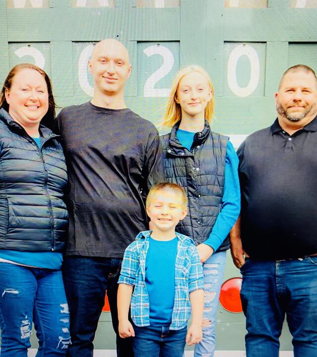 Noah Z and his family in front of a score board