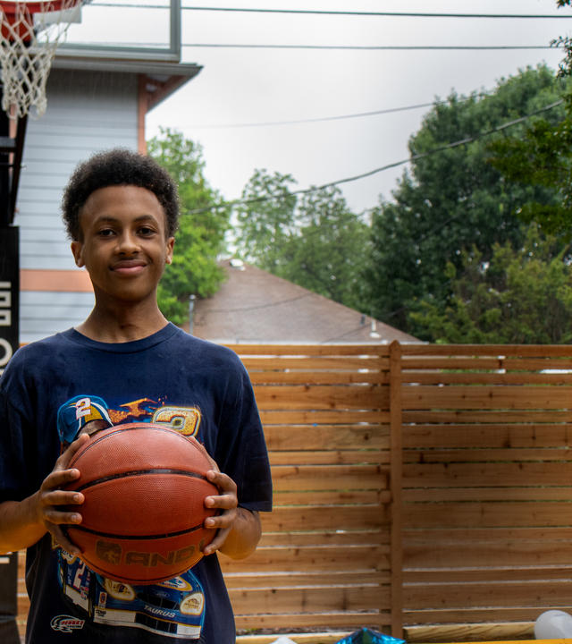 Wish Kid Solomon holding a basketball on his new basketball court