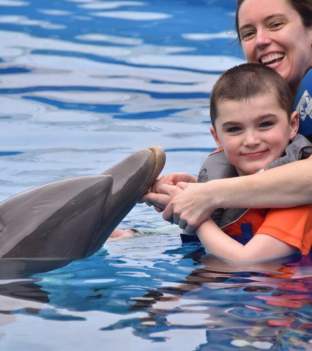 Gavin and his mom swim with a dolphin