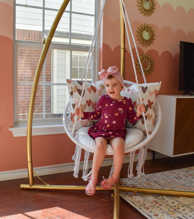 Wish kid Elise sitting on her swinging chair in her new playroom.