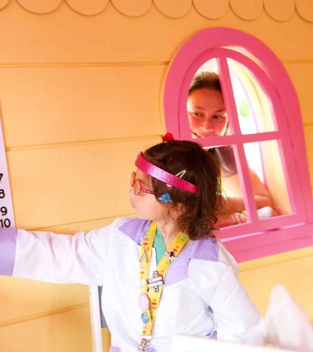 Dr. Penny pointing at eye chart while mom looks on